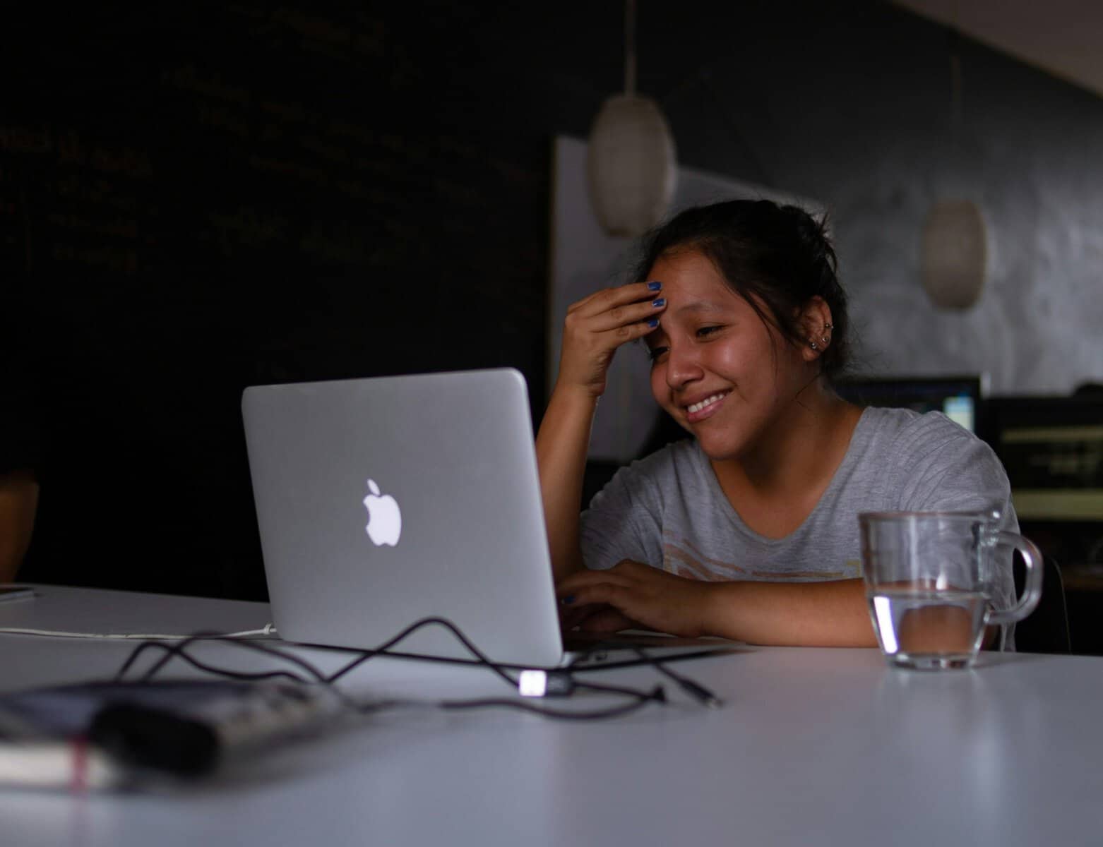Young woman laughing with relief while using a laptop at her desk, feeling supported in her autoimmune journey