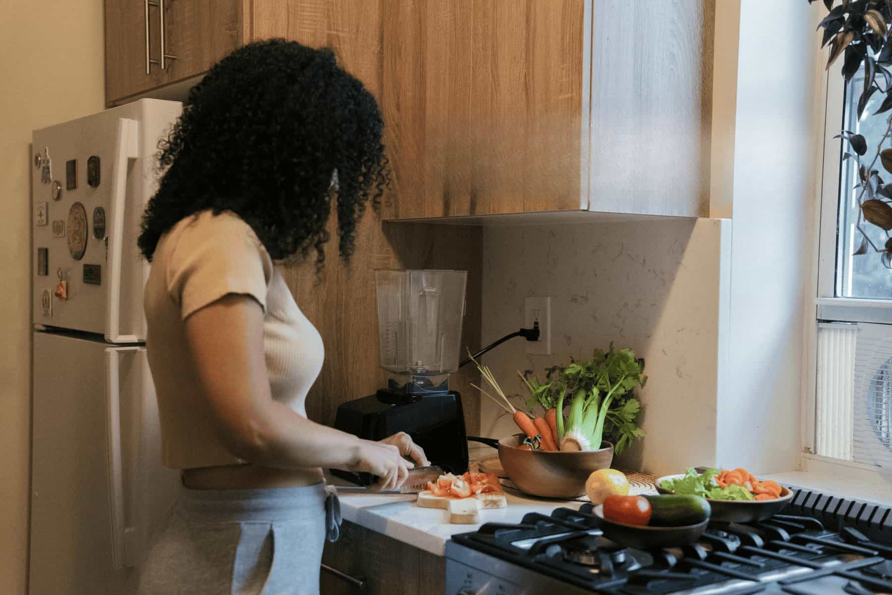 Woman preparing healthy vegetables in modern kitchen for autoimmune journey.