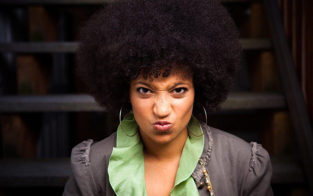 Bold woman with large afro making a playful, fierce face outdoors in Ireland.