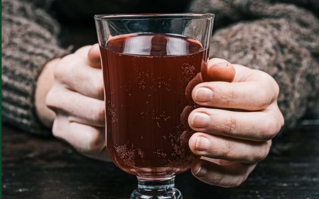 A person holding a glass of traditional Irish berry cordial.