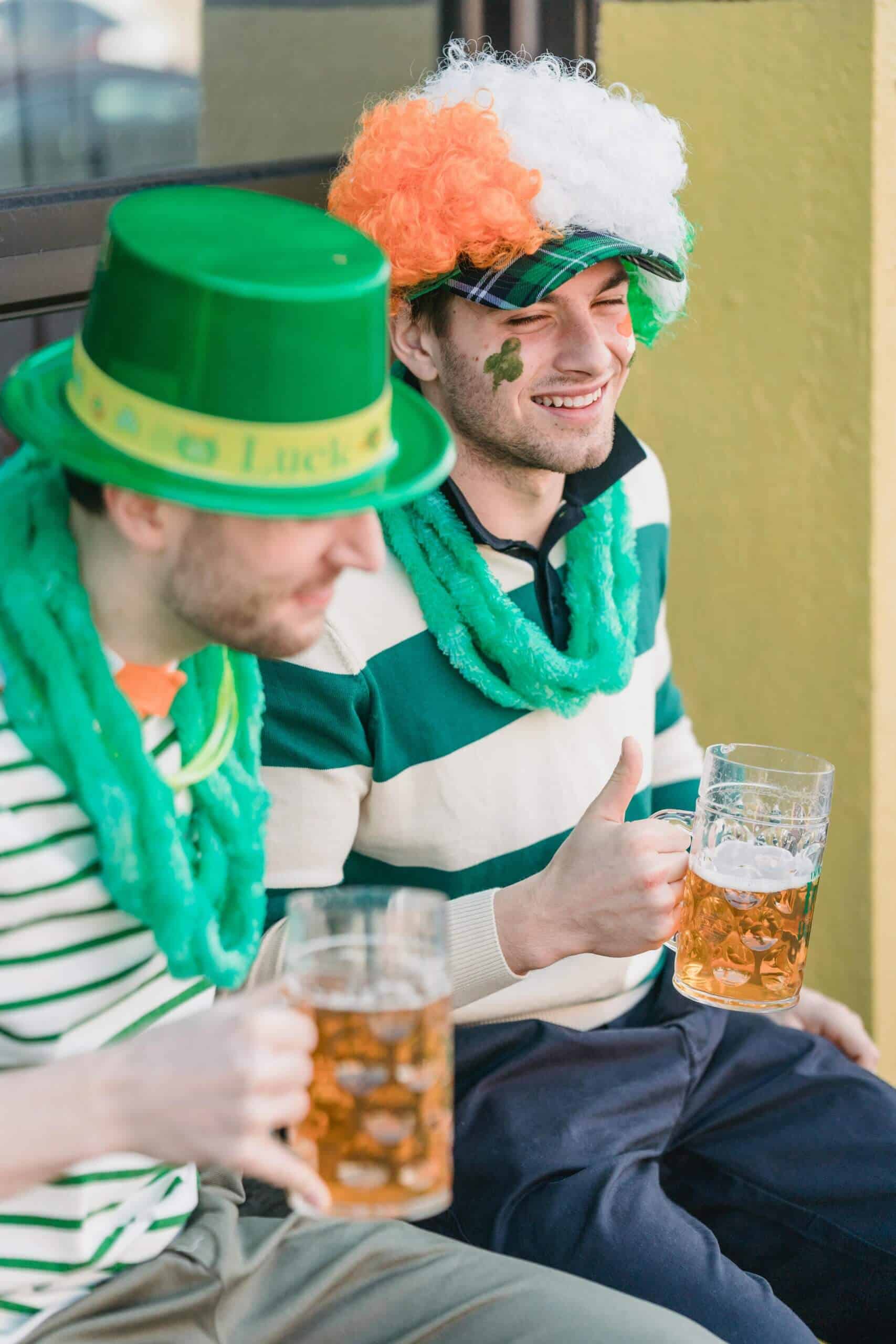 Festive friends celebrating St. Patrick's Day outdoors in Ireland, wearing green hats and face paint, enjoying beer and Irish culture.
