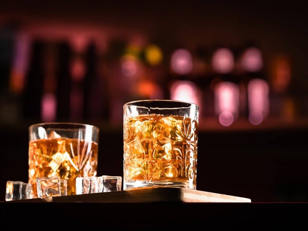 Amber whiskey glasses with ice, illuminated in a cozy bar setting in Ireland.