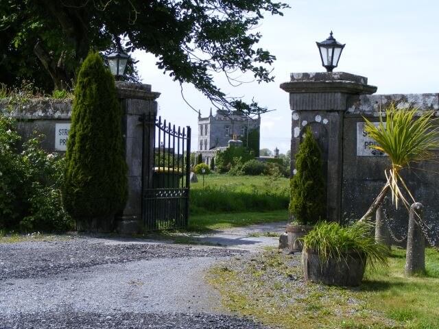 Rustic garden gate with stone pillars and greenery, inviting exploration of Irish heritage sites.