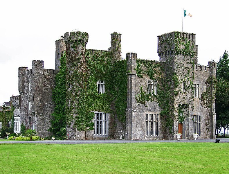 Ancient Irish castle covered in green ivy with a lush lawn in front, showcasing Ireland’s rich history and scenic beauty.
