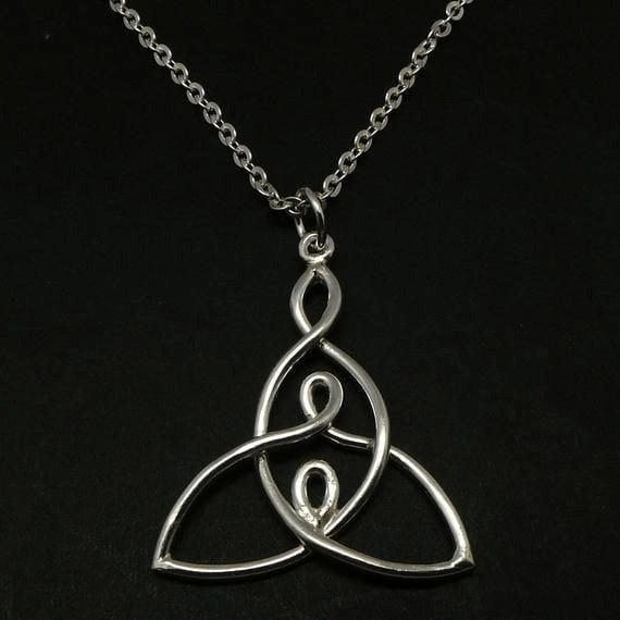 Delicate silver Celtic trinity knot pendant necklace on black background.