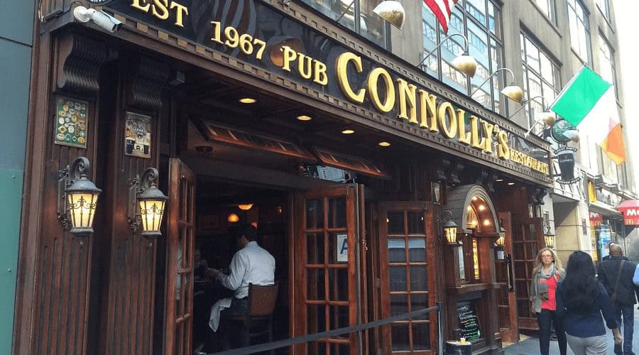 Cozy Irish pub exterior with warm lighting and wooden accents in a busy city street.