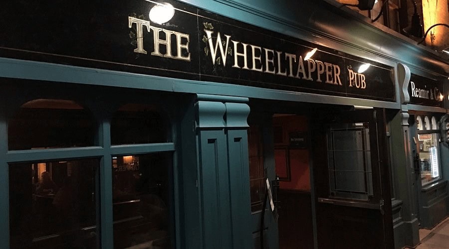 Cozy Irish pub with dark exterior, illuminated signage, and welcoming atmosphere.