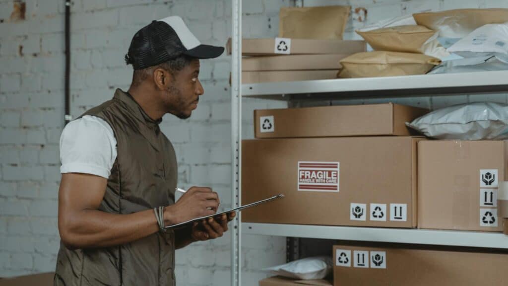 Man inspecting packages in warehouse with cardboard boxes.