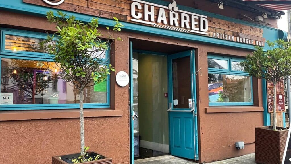 Colorful Irish burger bar storefront with blue accents and potted trees.