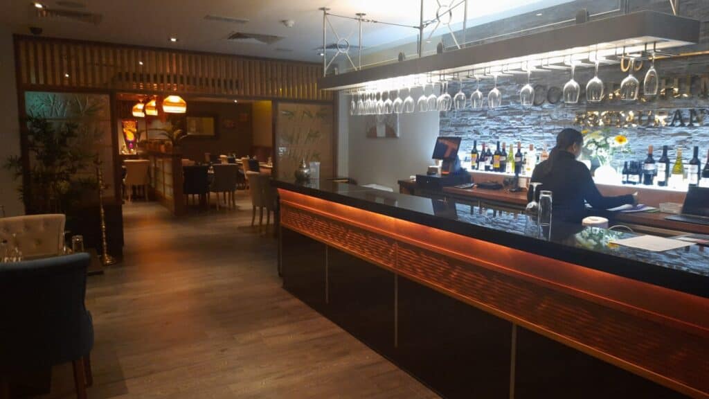 Cozy Irish restaurant interior with wooden décor and wine bottles behind the bar.