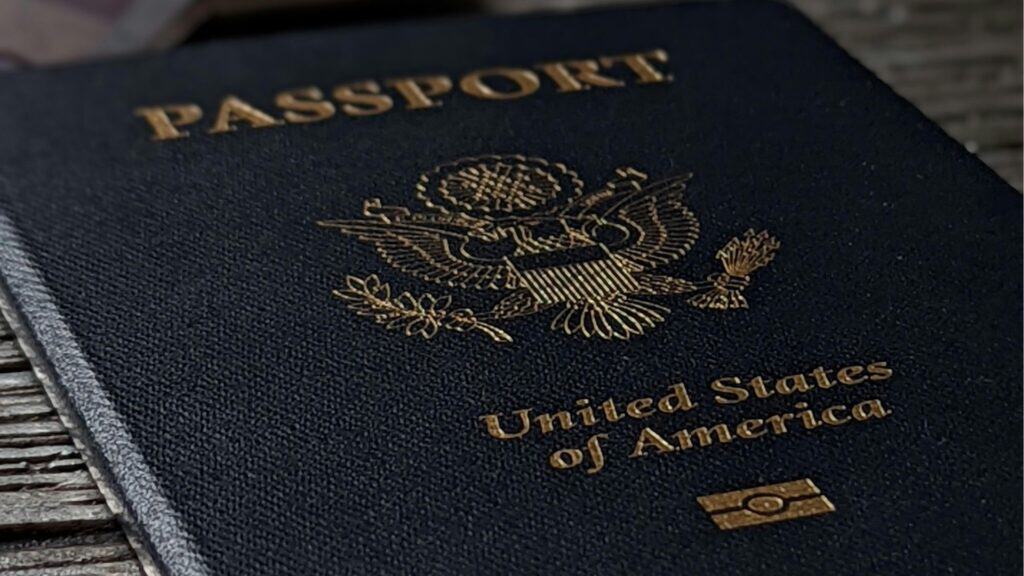 Passport with U.S. emblem on cover lying on wooden surface.