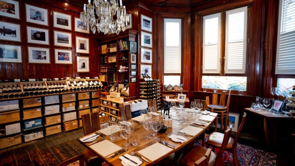 A cozy, elegant Irish restaurant with a wine display, wooden walls, and a chandelier, set for a fine dining experience.