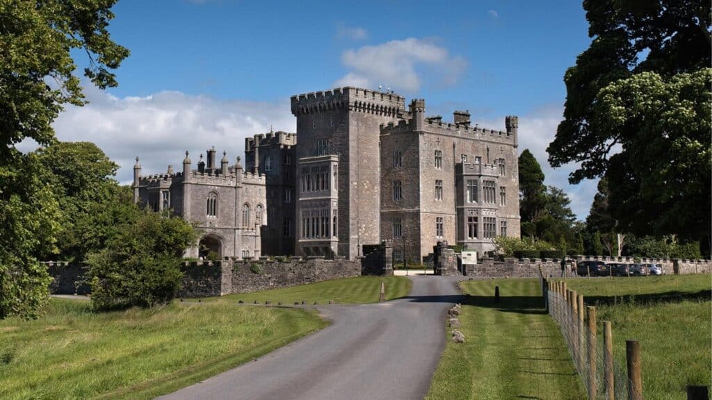 Majestic Irish castle surrounded by lush greenery and blue sky.
