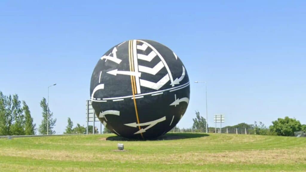 Colorful giant spherical road sculpture in a lush green park, representing Irish culture and travel.