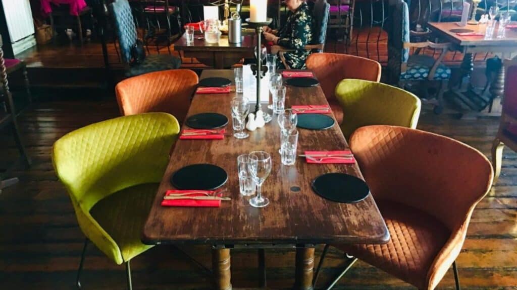 Vibrant dining chairs around a rustic restaurant table with place settings and glassware.