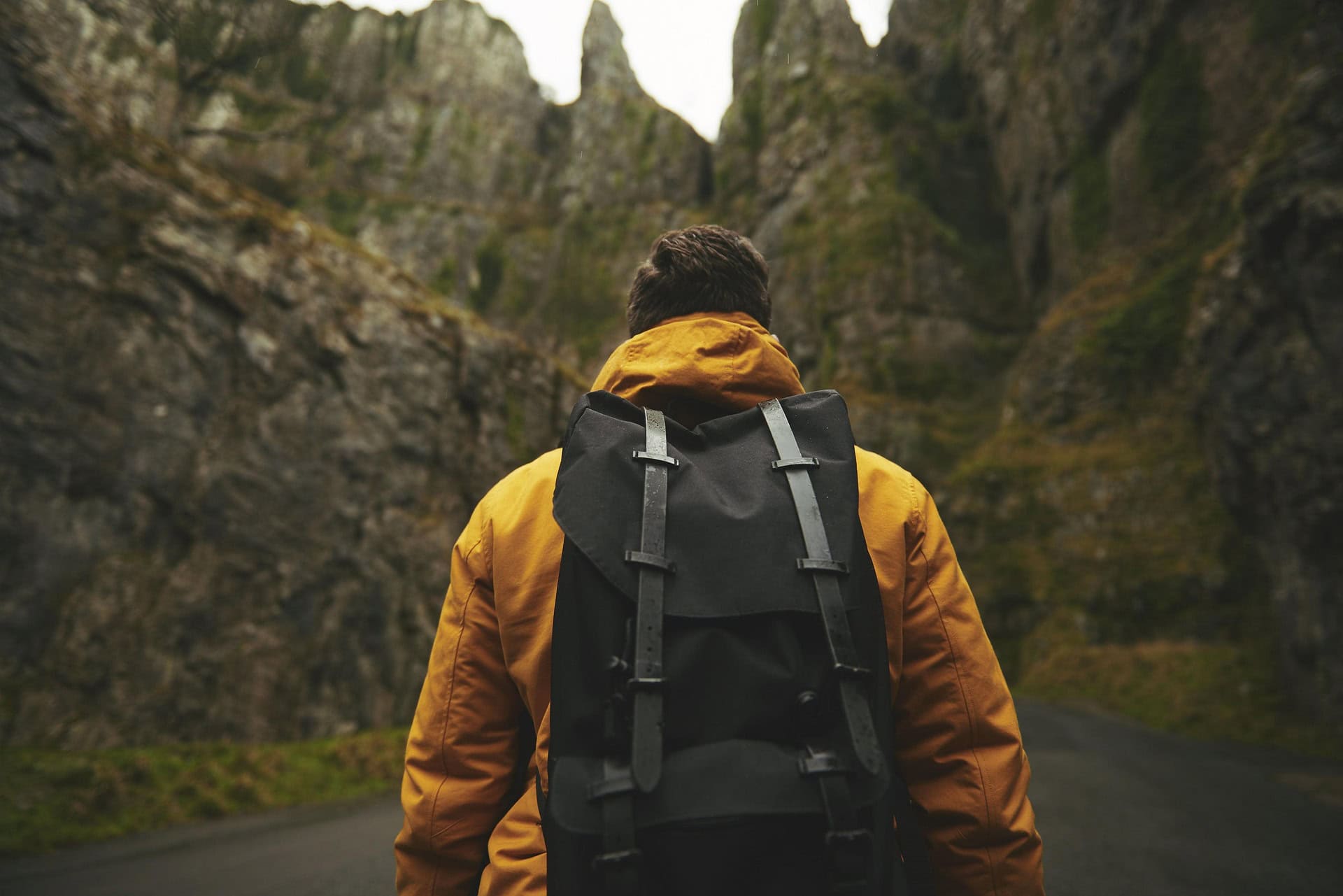 Wanderer in yellow jacket exploring rocky mountain pass in Ireland.