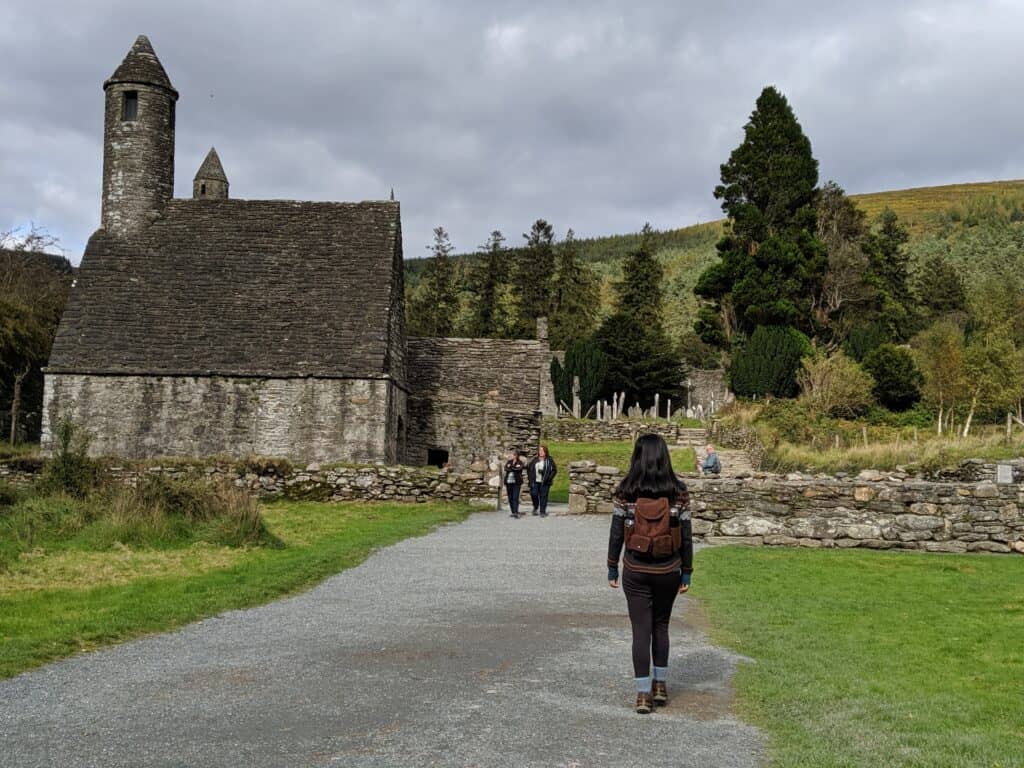 Ancient Irish church with visitors in a rural landscape.