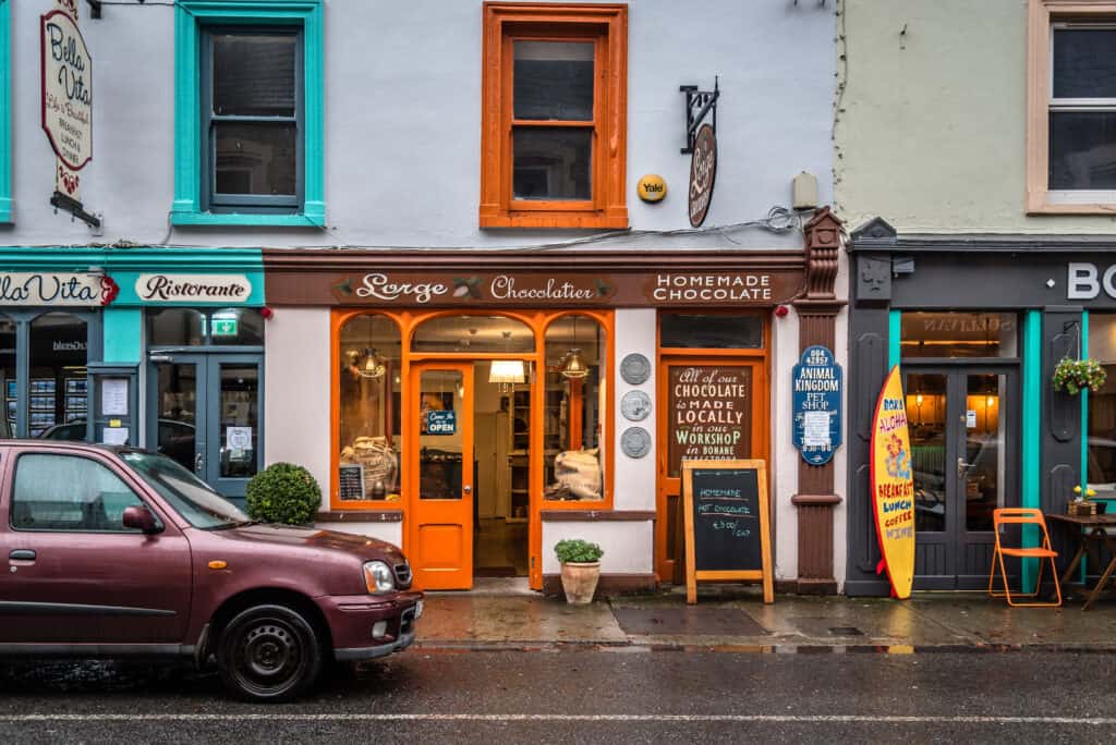 Colorful shopfronts on a rainy Irish street in Killarney, with a chocolate店.