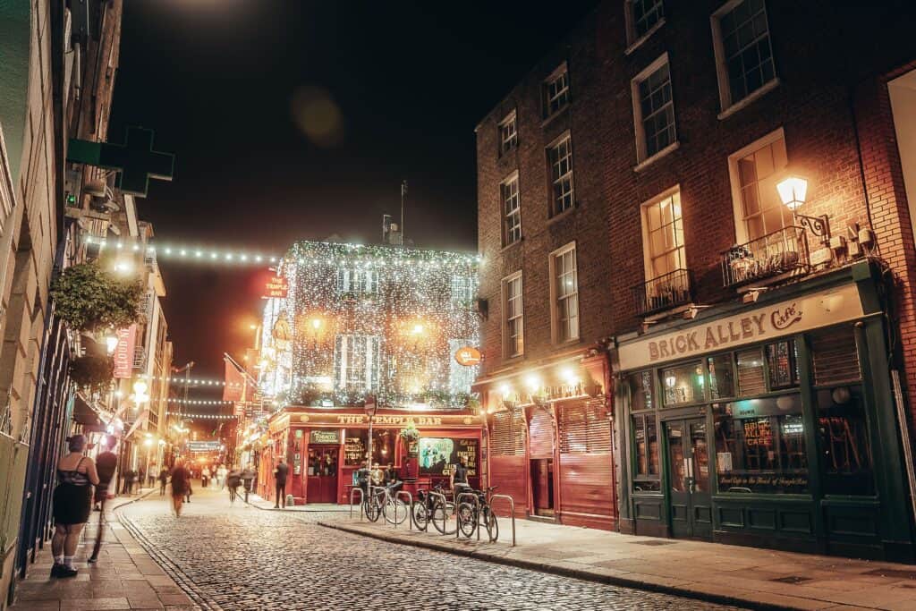 Illuminated city street at night showcasing bustling pedestrian walkways and vibrant nightlife.