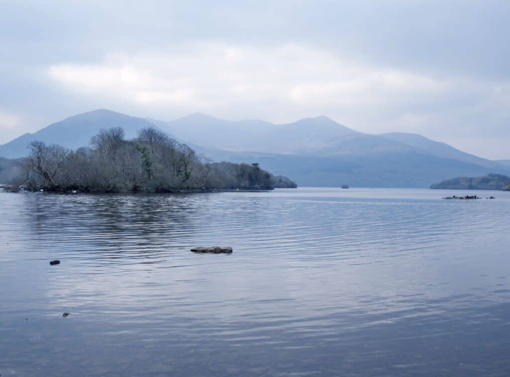 Tranquil lake and mountain scene in Killarney National Park, Ireland under a cloudy sky.