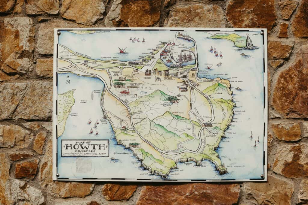 Detailed map of Howth, Dublin on a rustic stone wall, showcasing the scenic coastal area.