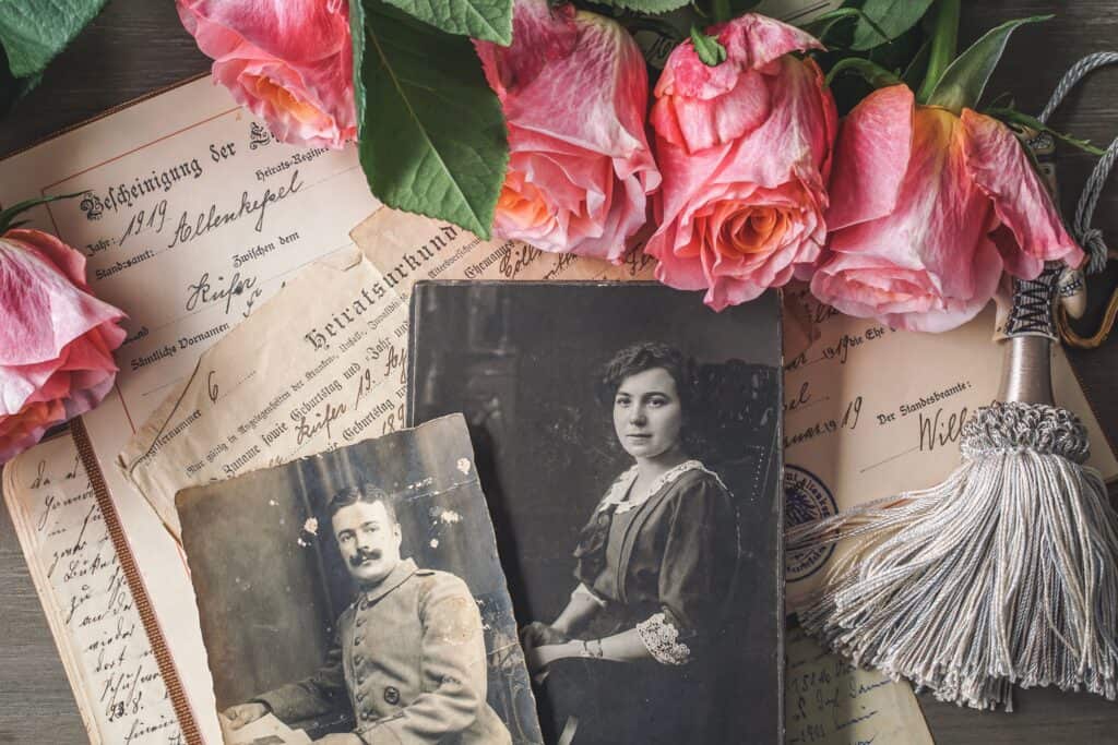 Antique family photographs with pink roses and historic documents.