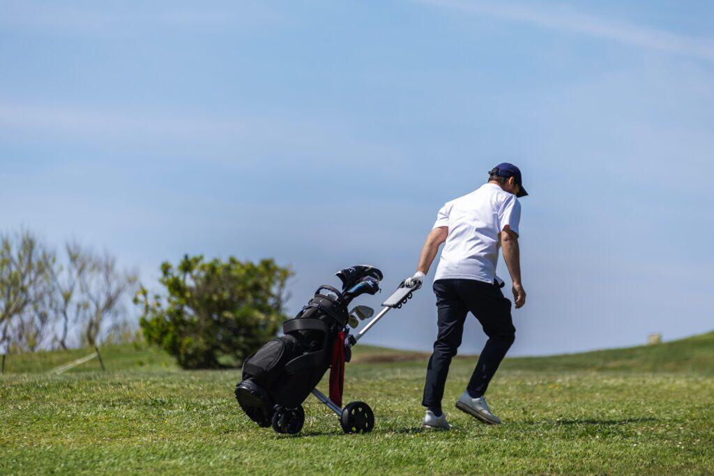 Man playing golf on Irish course with golf bag and trolley.