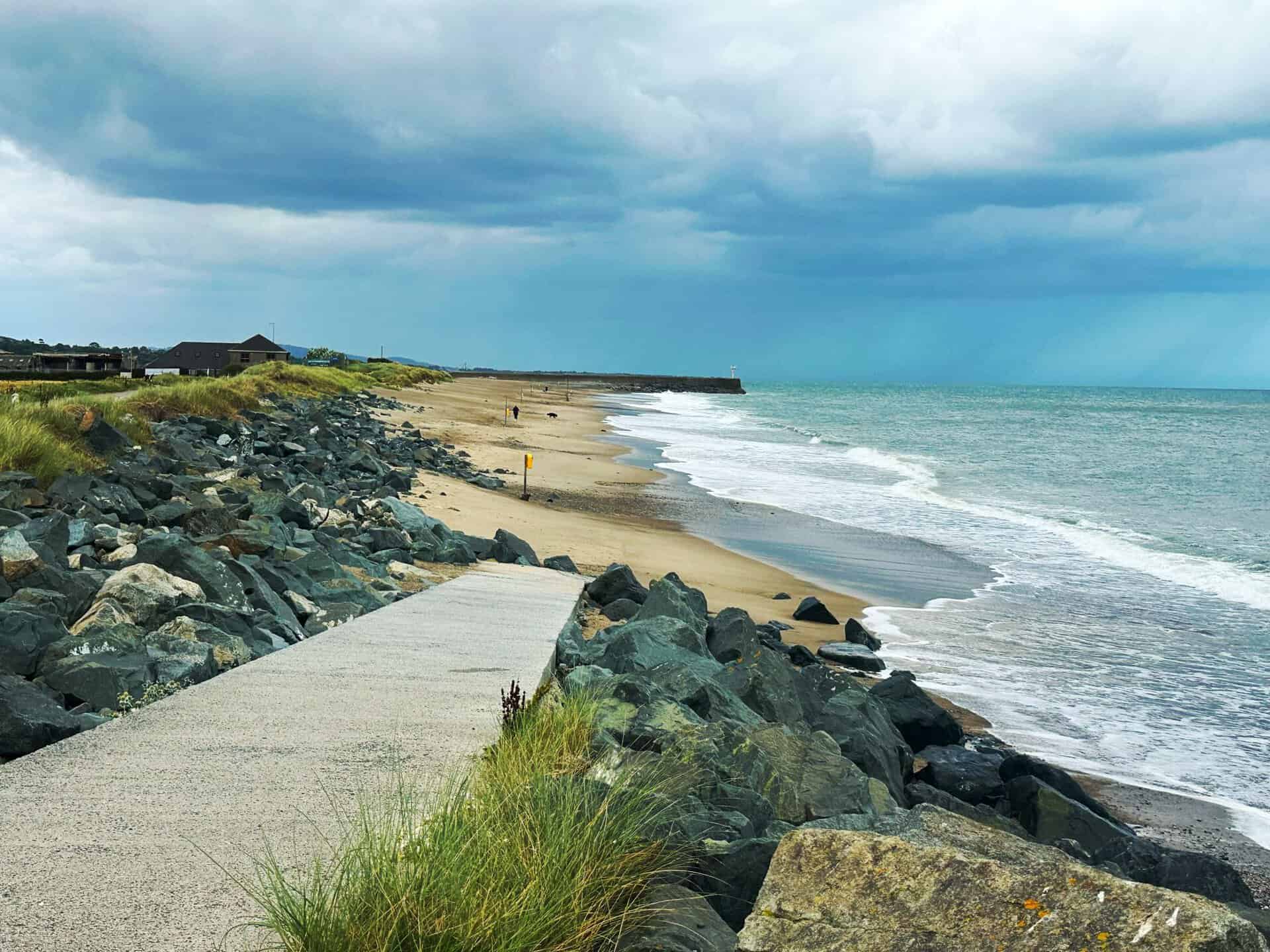 A beautiful view of Wicklow beach with rocky pathway and cloudy sky, ideal for travel inspiration.