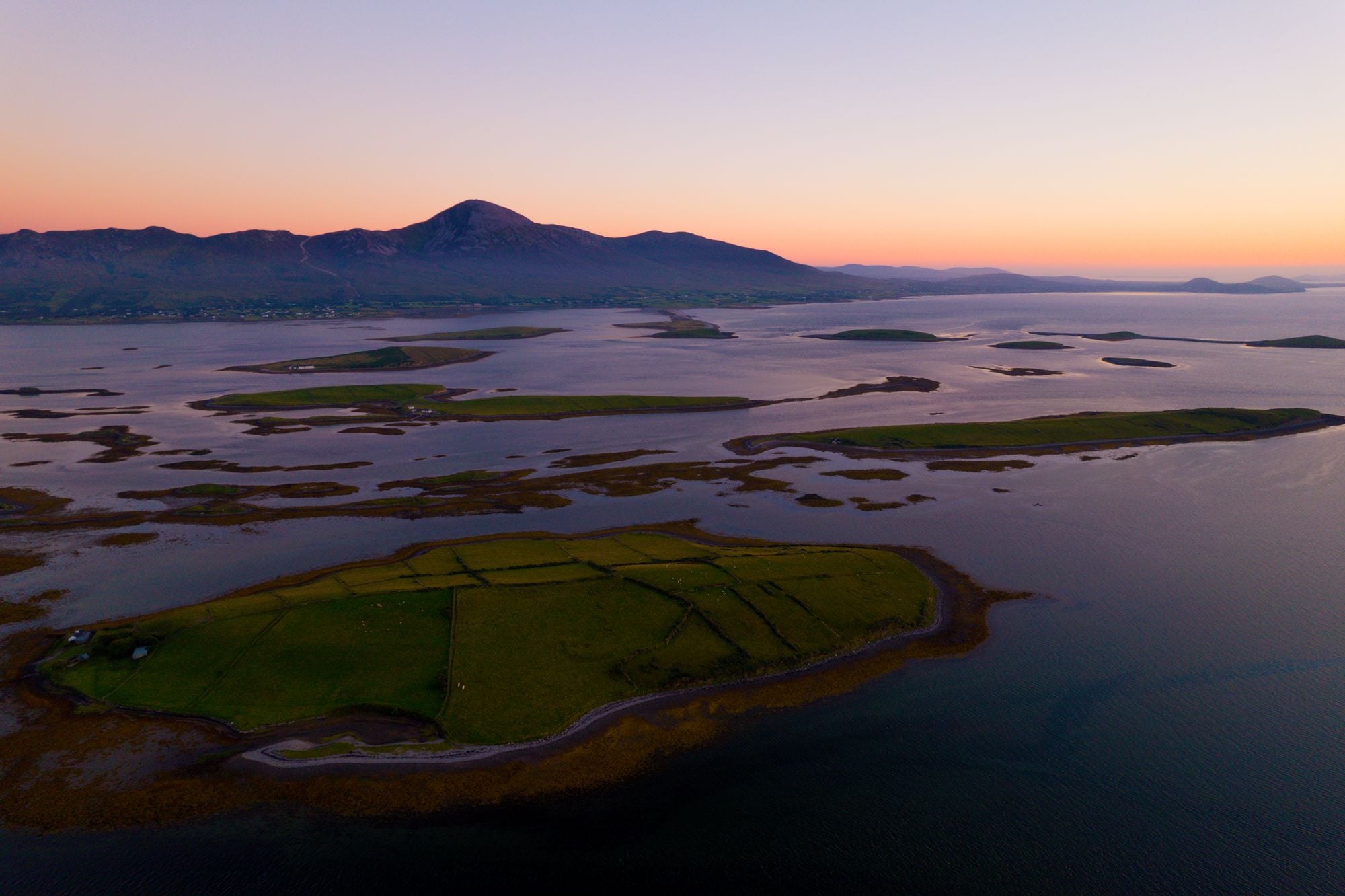 A breathtaking aerial view of islands and mountains in Clew Bay, Ireland at sunset, showcasing natural beauty.
