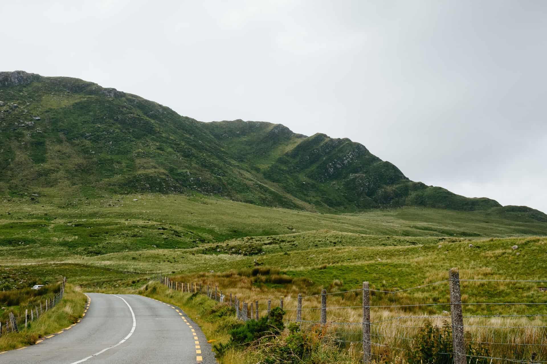A pastoral road winding through the lush greenery of Killarney National Park in Ireland.