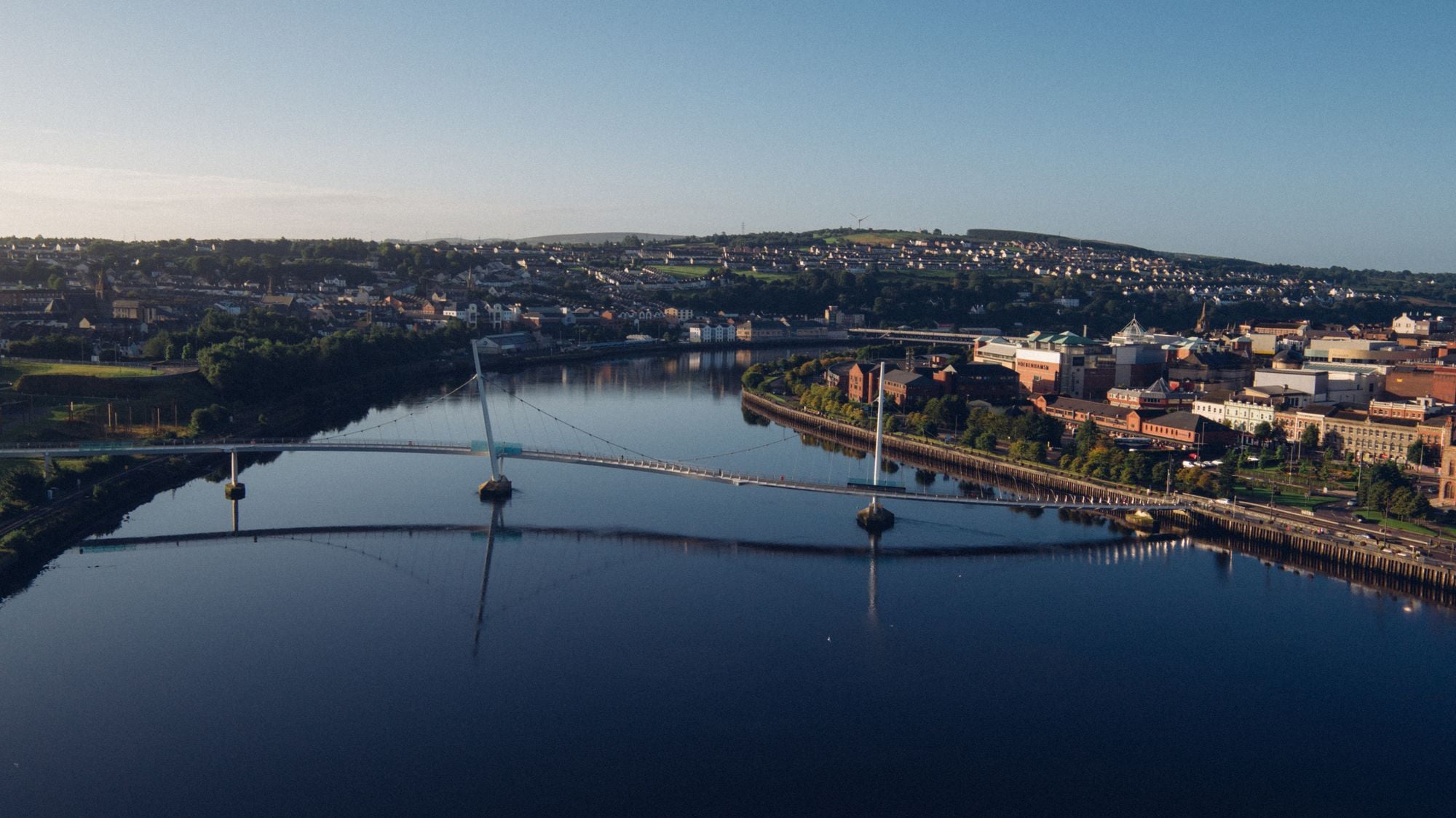 A stunning aerial view of a cityscape with a river, featuring a modern bridge connecting the riverbanks.