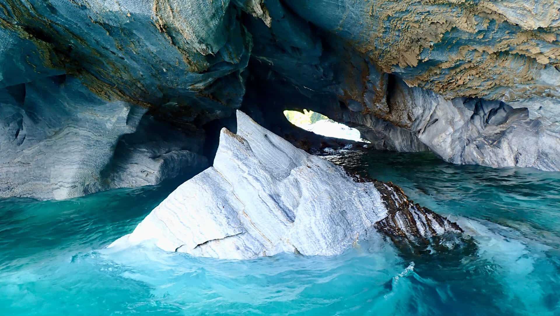 Beautiful marble cave formations above turquoise waters, creating a serene natural scene.