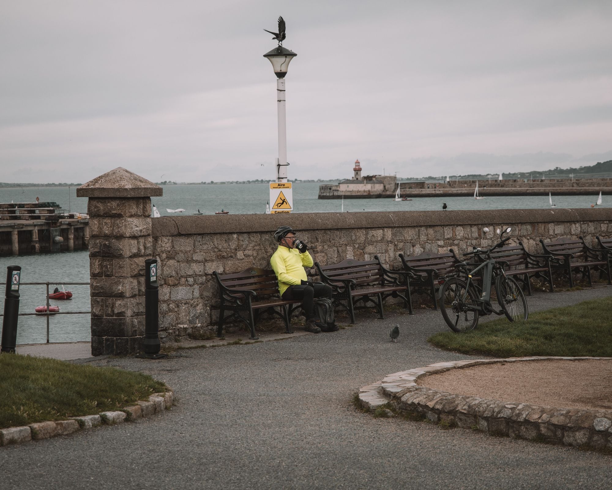 Cyclist enjoying a break by the seaside in Dublin, Ireland. Scenic harbor view with benches and bicycles.