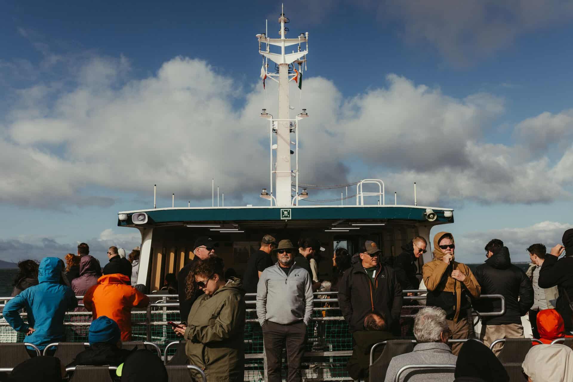 Group of tourists on a ferry in County Galway, Ireland, under a partly cloudy sky.