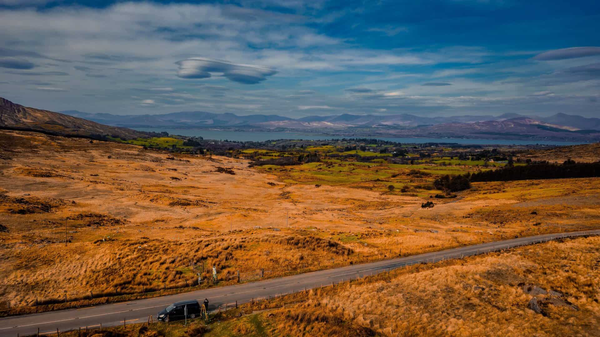 Scenic Irish countryside with a car on a rural road.