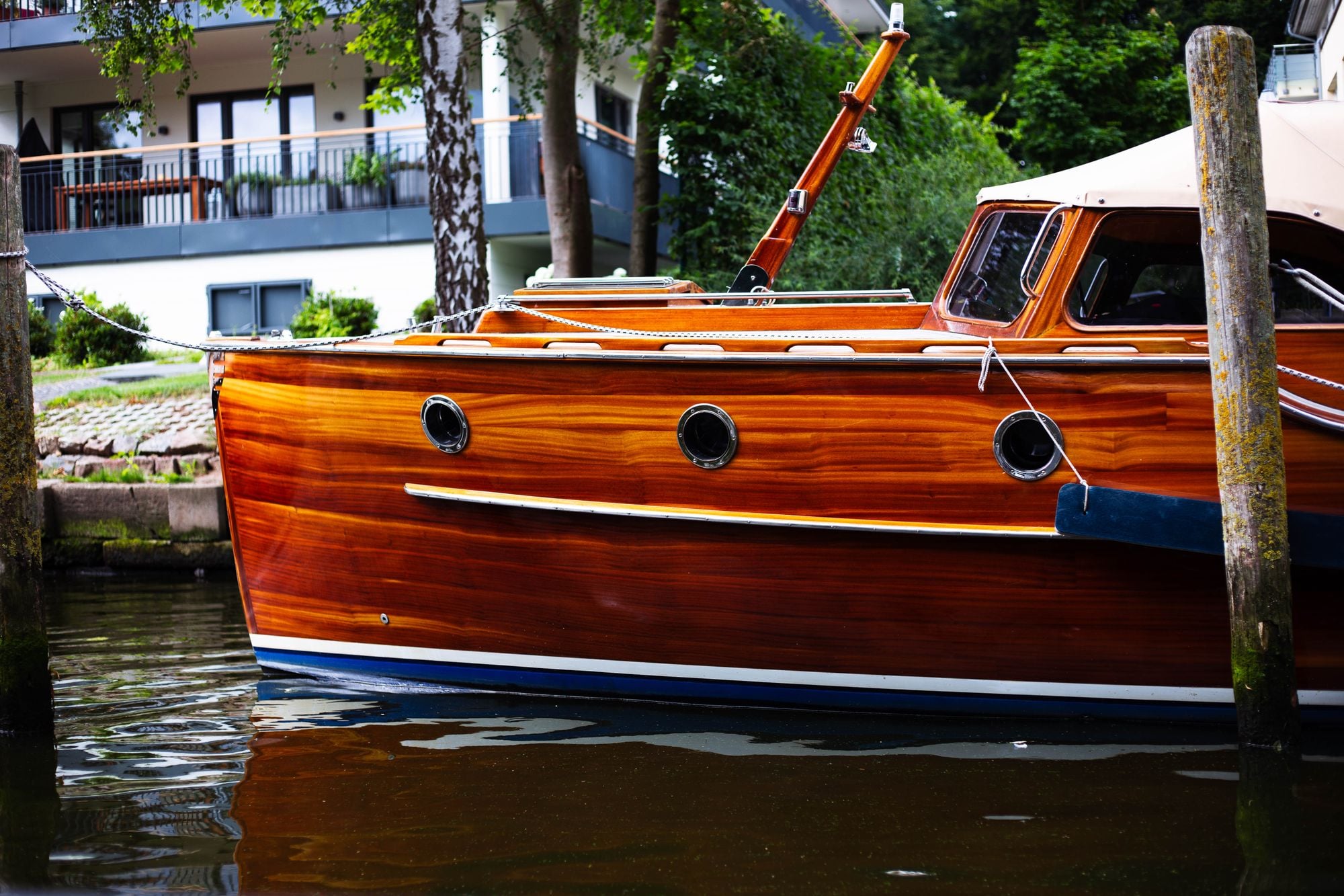A classic wooden boat moored at a dock in Lübeck, surrounded by serene waters and greenery.