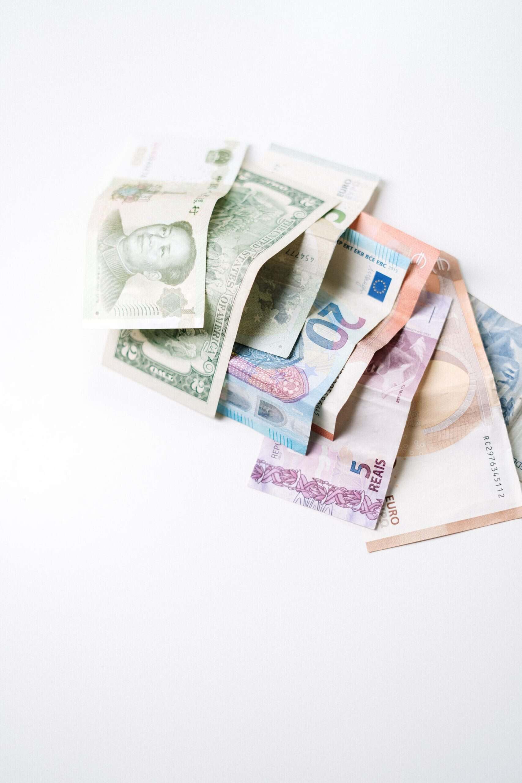 A diverse collection of international banknotes arranged on a white surface, showcasing global currencies.
