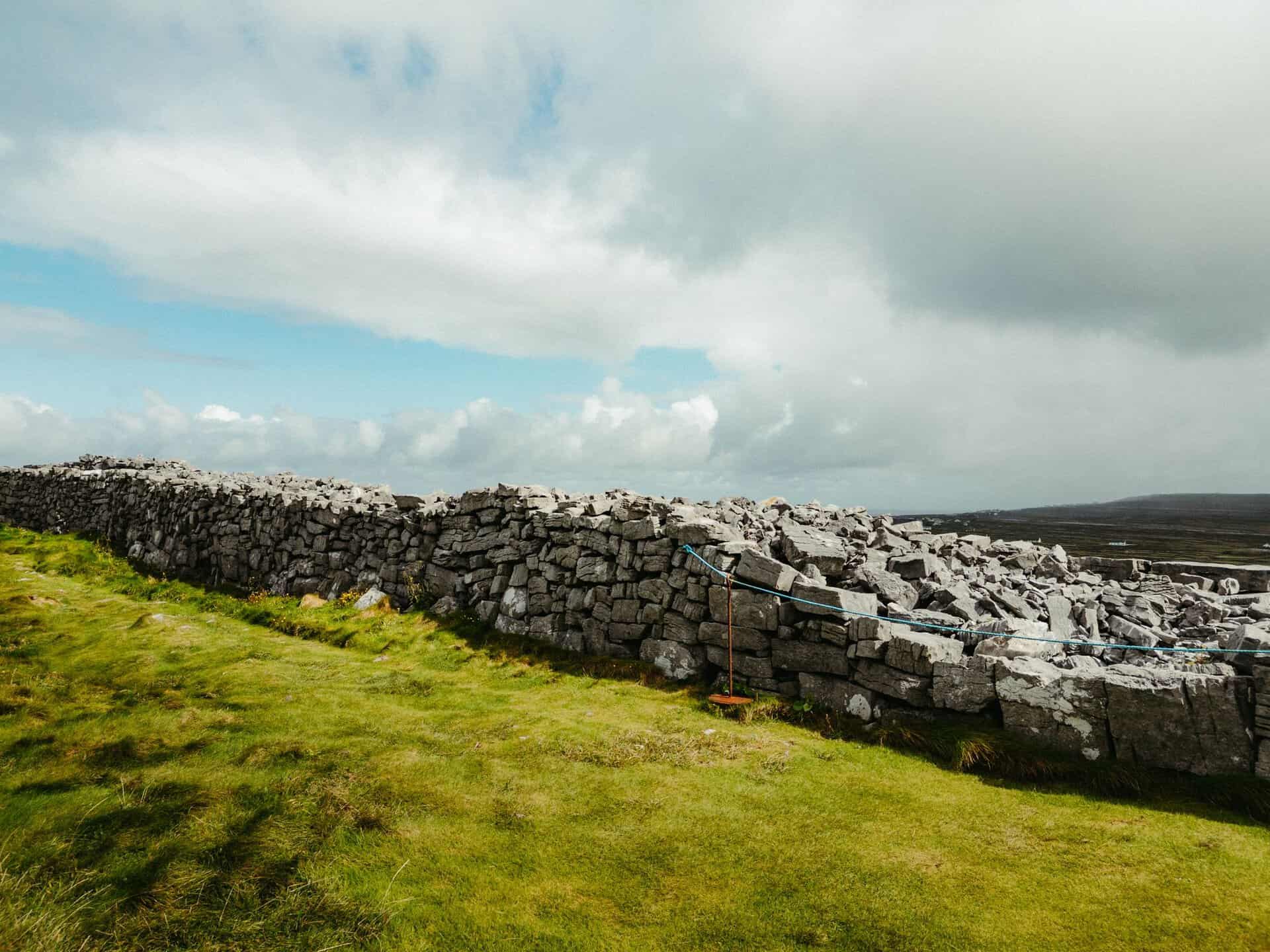 A scenic shot of a traditional stone wall in County Clare, Ireland under a cloudy sky.