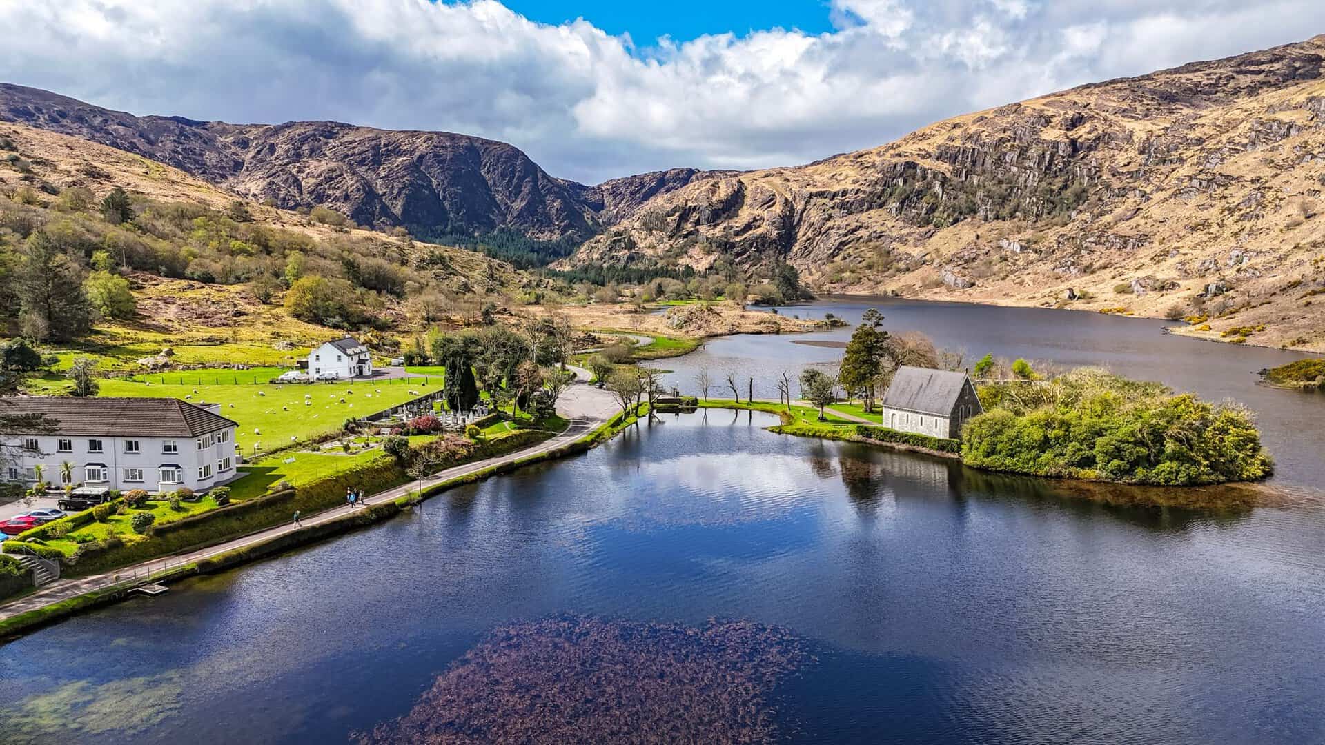 Aerial view of Gougane Barra's lake, chapel, and mountains in County Cork, Ireland.