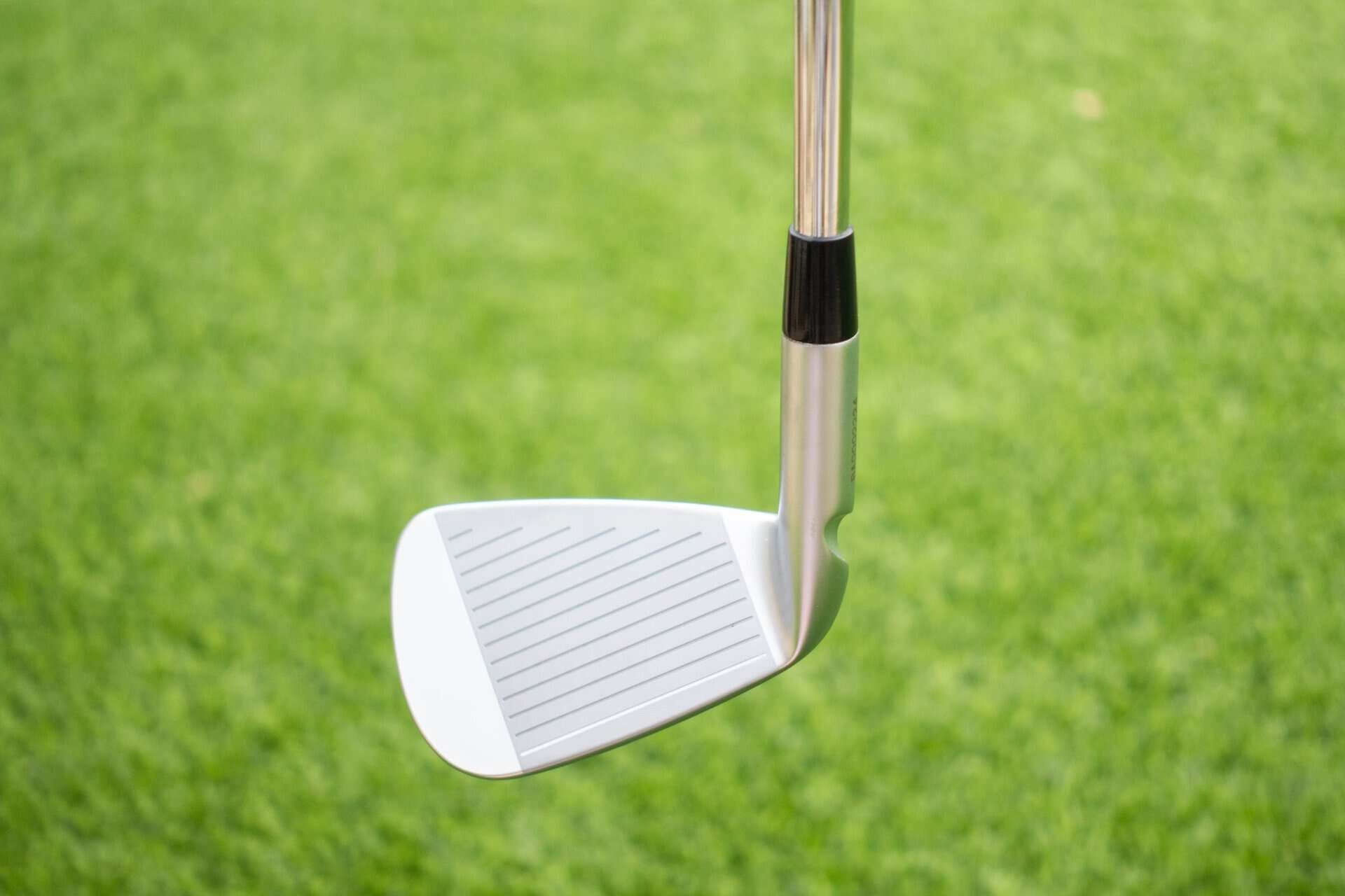 A golf iron resting above grass