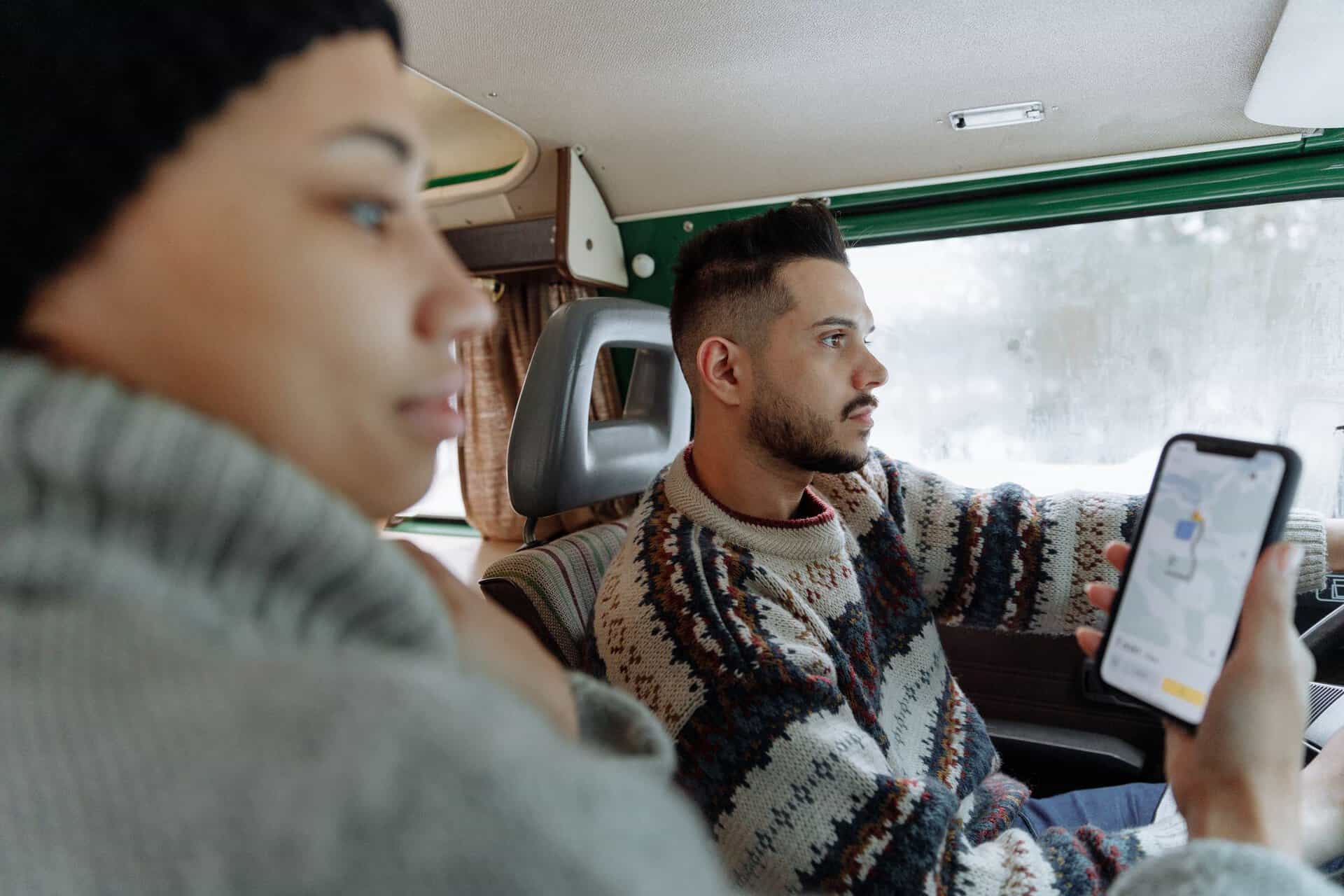 Passengers checking a map on a phone inside a campervan