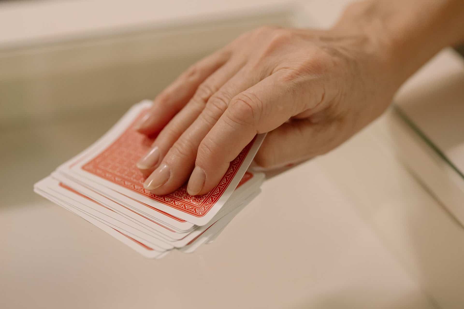 A hand picking up a standard deck of playing cards.