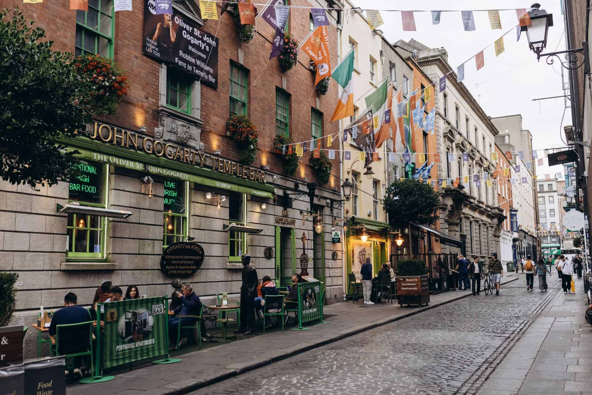 Dublin street with pubs, flags, and pedestrians.