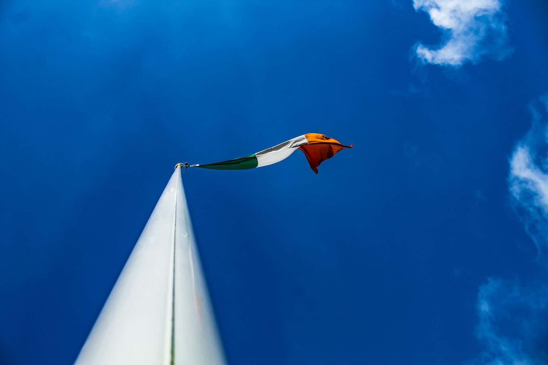 The Irish green, white and orange tricolour flying against a blue sky.