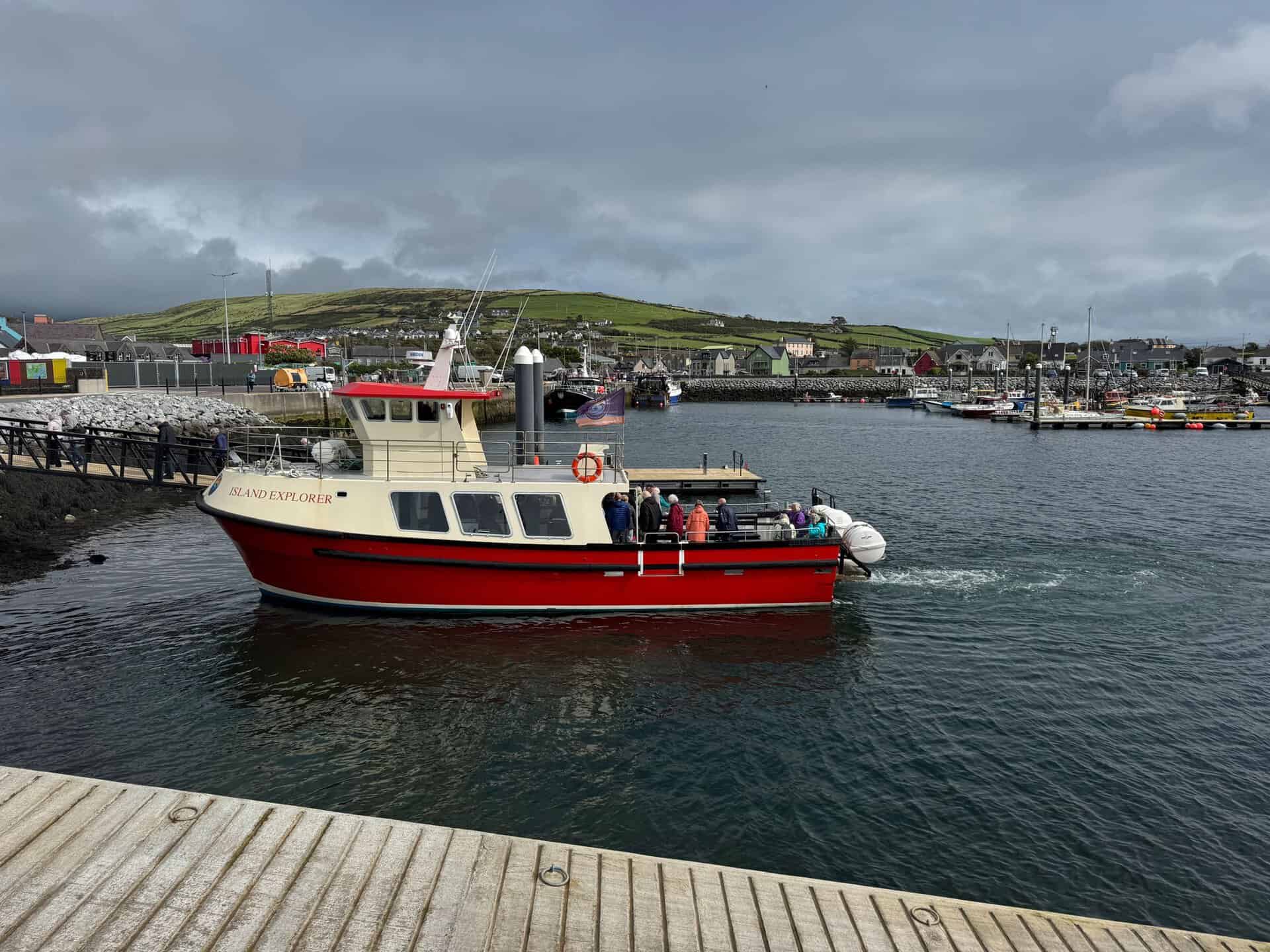 Red Island Explorer boat cruising in Dingle Harbor, Ireland with scenic coastal views.