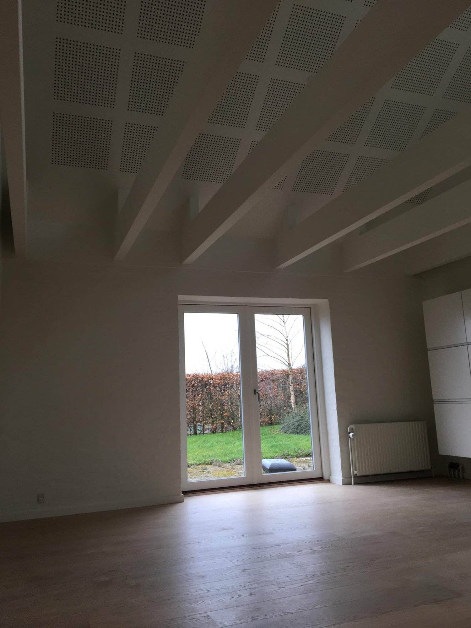 Moderne stue med store glasdøre og loftsbjælker.