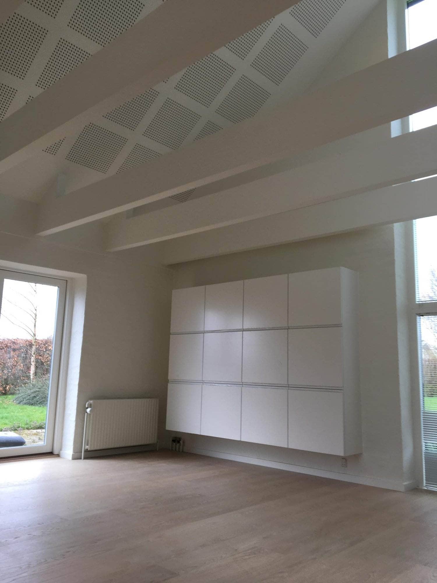 Interiørbillede af et moderne hjem med hvide vægge og store vinduer.
