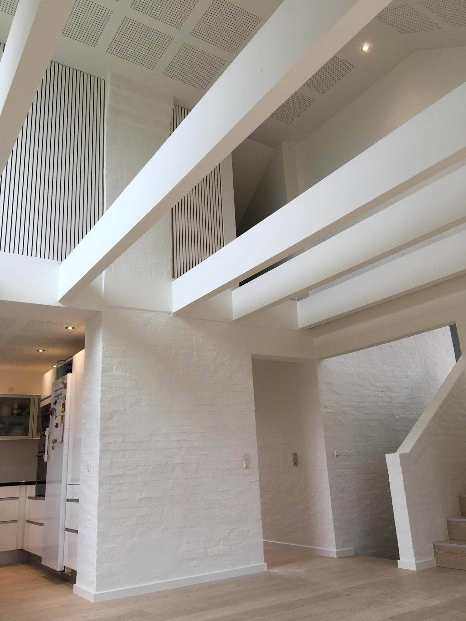 Moderne indretning af stue med hvide vægge og loftsdetaljer.