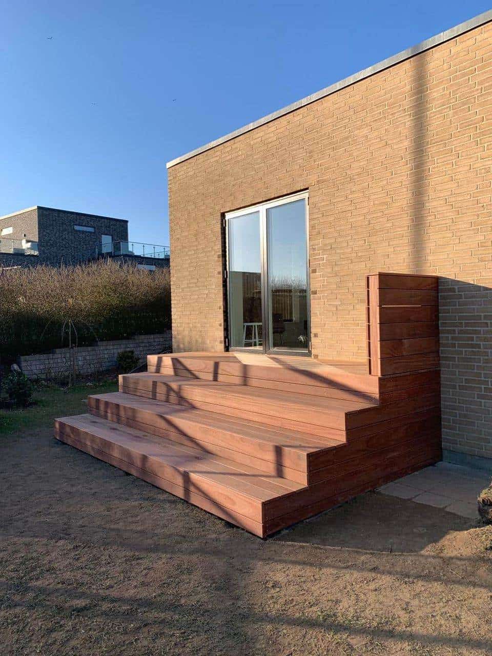 Trætrappe og dørhul til udendørs terrasse i moderne bolig.