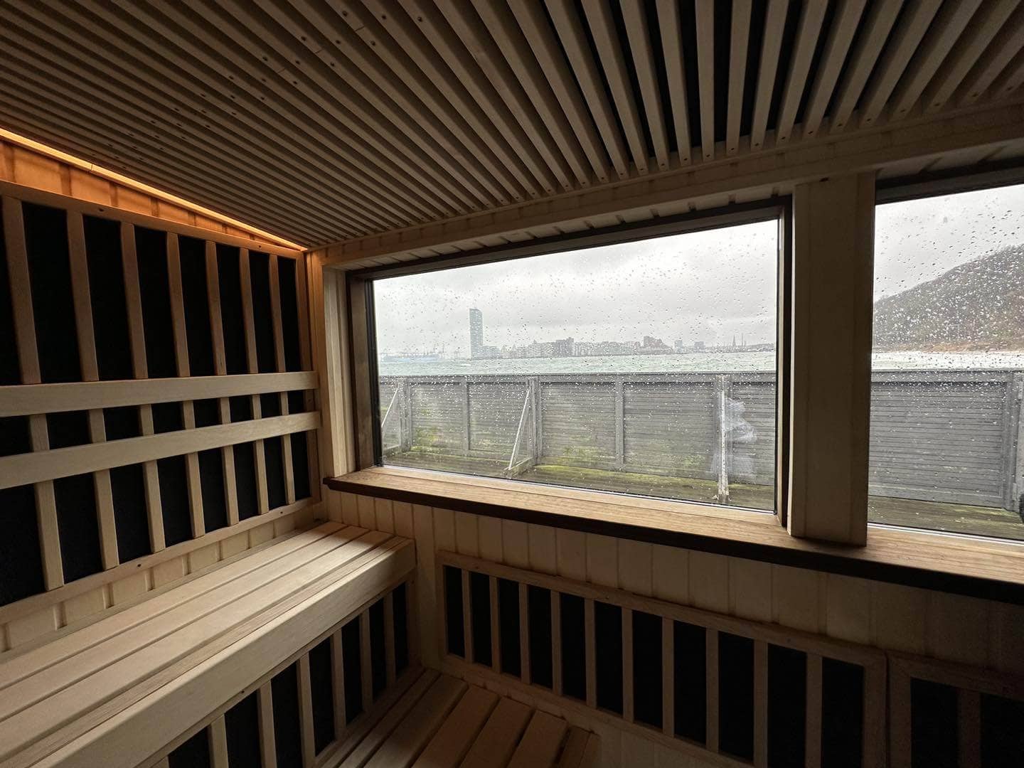 Udendørs sauna i asp-træ med stor vinduesfront og moderne design. Perfekt til afslapning i naturen.